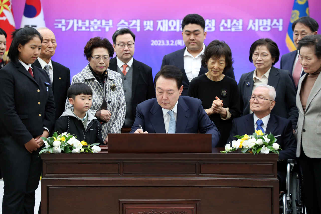 President Yoon Suk Yeol (center) signs a bill to approve the revision of the Government Organization Act, aimed at elevating the Ministry of Patriots and Veterans Affairs and creating a new agency to support Korean diaspora as he is surrounded by participants at the signing ceremony held Thursday in his office in Seoul. (Yonhap)