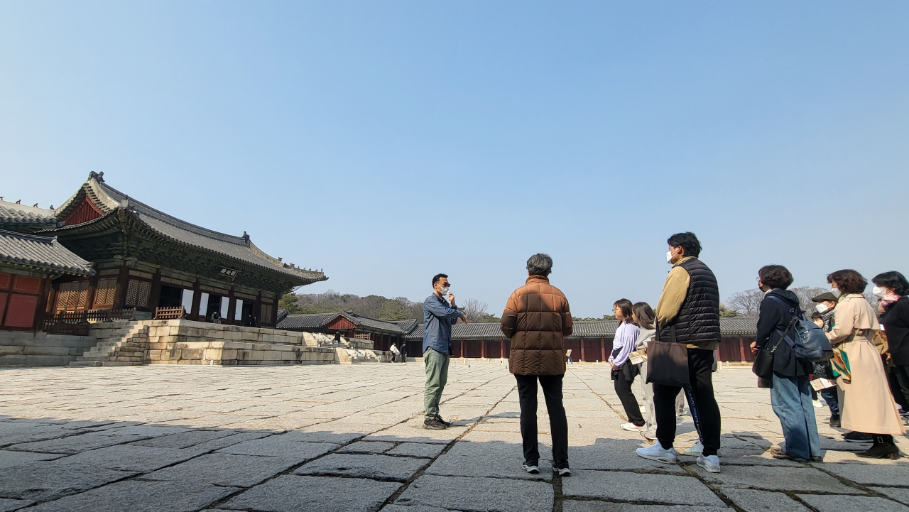 Visitors stop to listen to the guide in front of the hall Myeongjeongjeon at Changgyeonggung during a special tour of the palace on Sunday. (Kim Hae-yeon/ The Korea Herald)