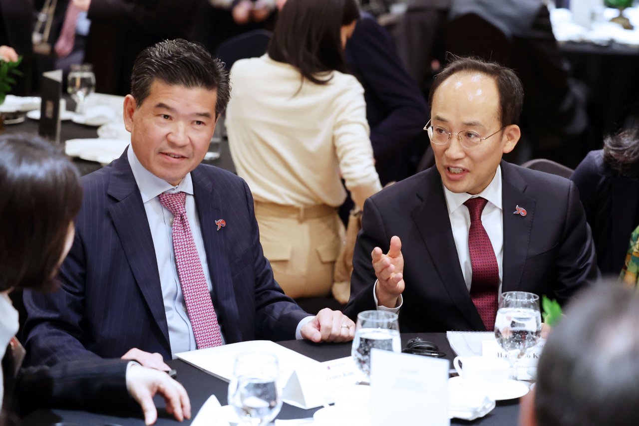 AmCham Chairman and CEO James Kim (left) and Finance Minister Choo Kyung-ho talk during a special luncheon at a Seoul hotel on Wednesday. (Yonhap)