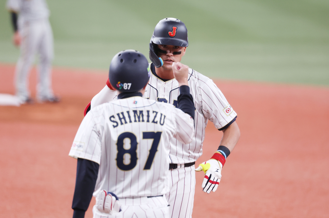 Lars Nootbaar of Japan (right) celebrates an RBI single against the Hanshin Tigers during an exhibition game for the World Baseball Classic at Kyocera Dome Osaka in Osaka on Monday. (Yonhap)
