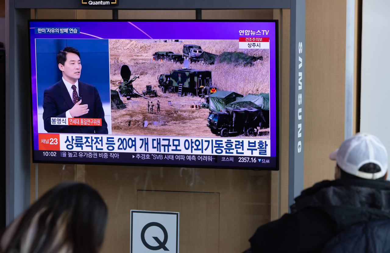 Passersby watch a news report on North Korean ballistic missile launches on March 14 at Seoul Station in Seoul. (Yonhap)