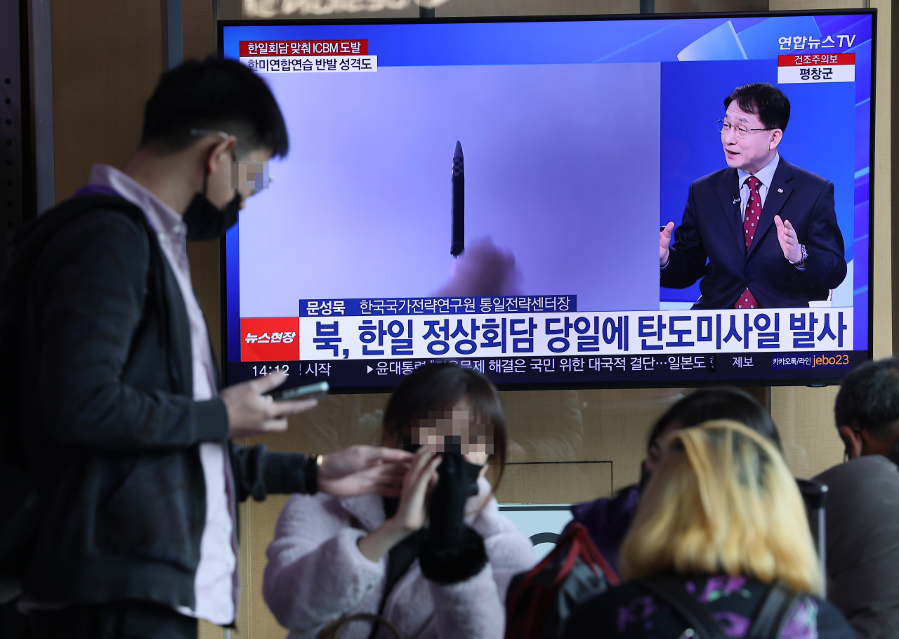 Passersby watch a news report on North Korea's launch of an intercontinental ballistic missile on March 16 at Seoul Station in Seoul. (Yonhap)