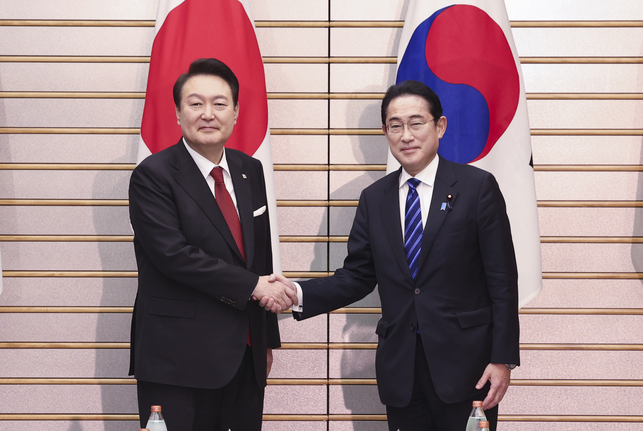South Korean President Yoon Suk Yeol (left) shakes hands with Japanese Prime Minister Fumio Kishida at the prime minister's office in Tokyo on Thursday prior to the summit meeting. (Yonhap)