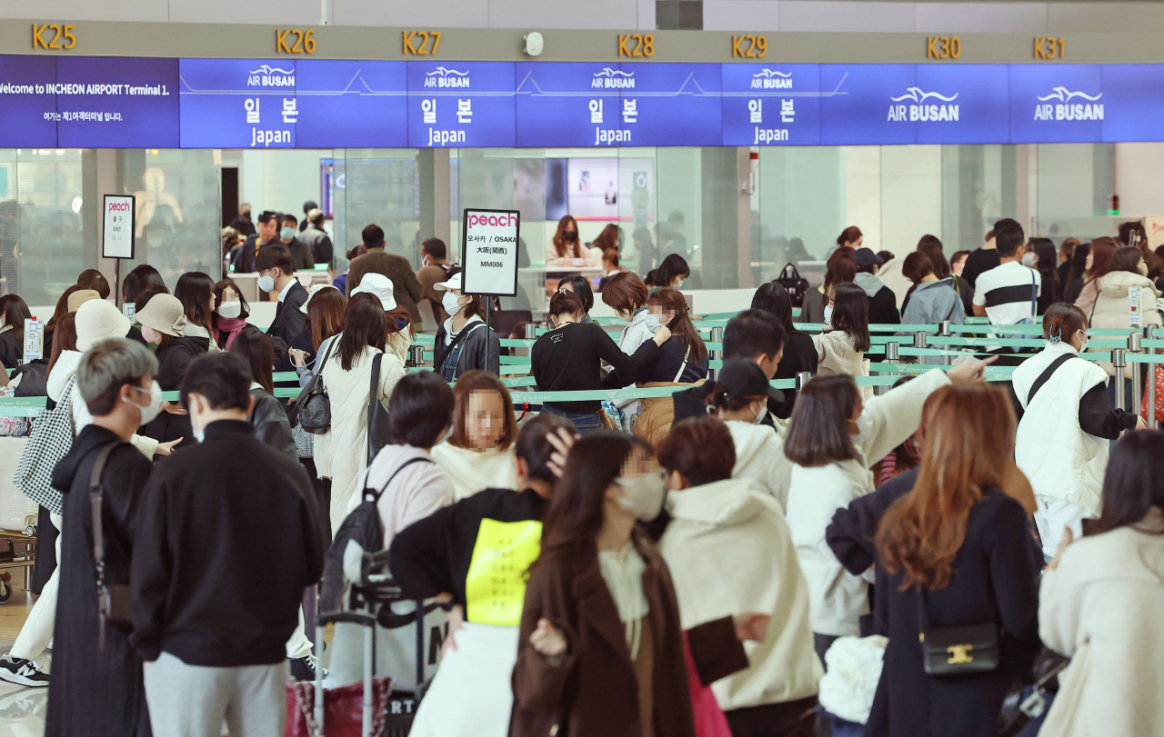 Passengers wait in a long line in front of check-in counters at Incheon International Airport. (Yonhap)
