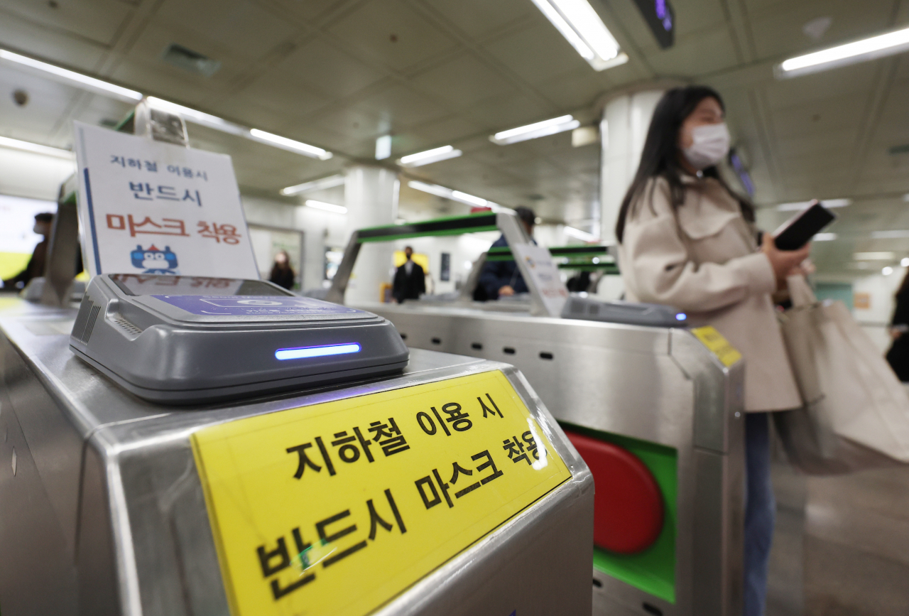 This file photo taken on March 15 shows a sign on a turnstile at a subway station in Seoul requiring passengers to wear face masks when boarding the subway. The mask mandate for public transportation will be lifted from March 20. (Yonhap)