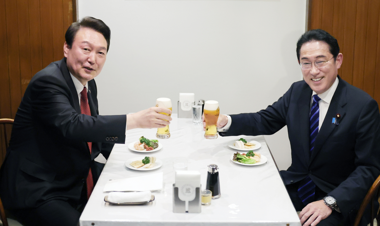 President Yoon Suk Yeol (L) and Japanese Prime Minister Fumio Kishida clink their glasses at a restaurant after their summit in Tokyo on March 16, 2023. (Yonhap)