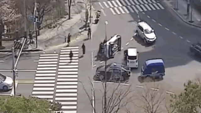 Pedestrians flip a car on its side on Tuesday in eastern Ulsan. (Ulsan Metropolitan Police)