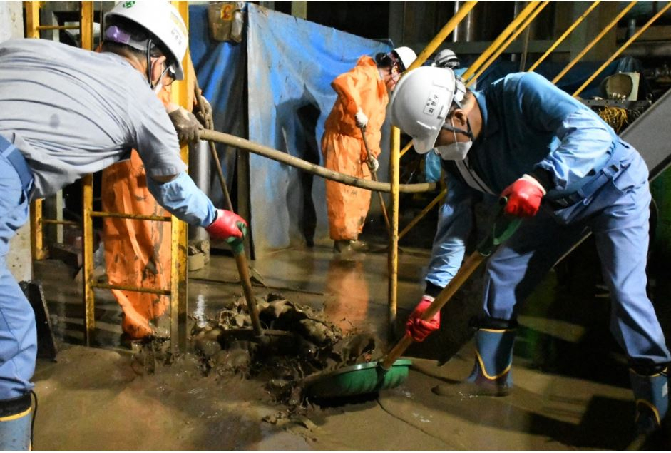 Posco Group Chairman Choi Jeong-woo (right) clears out mud at a rolling mill on Sept. 18 in the aftermath of a typhoon. (Posco)