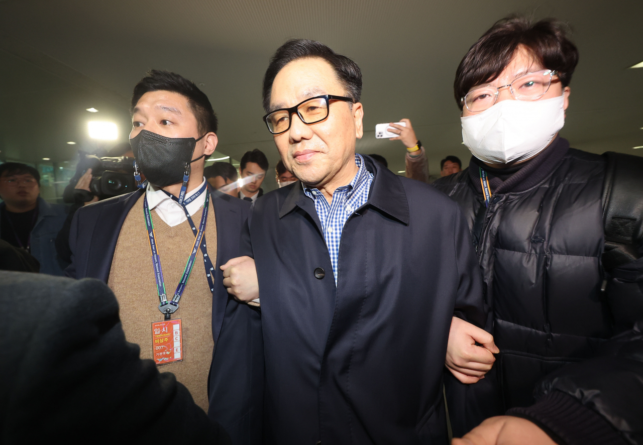 Prosecution officials arrest Cho Hyun-chun (at the center), a former head of the now-defunct Defense Security Command, at Incheon International Airport, west of Seoul, on Wednesday. (Yonhap)