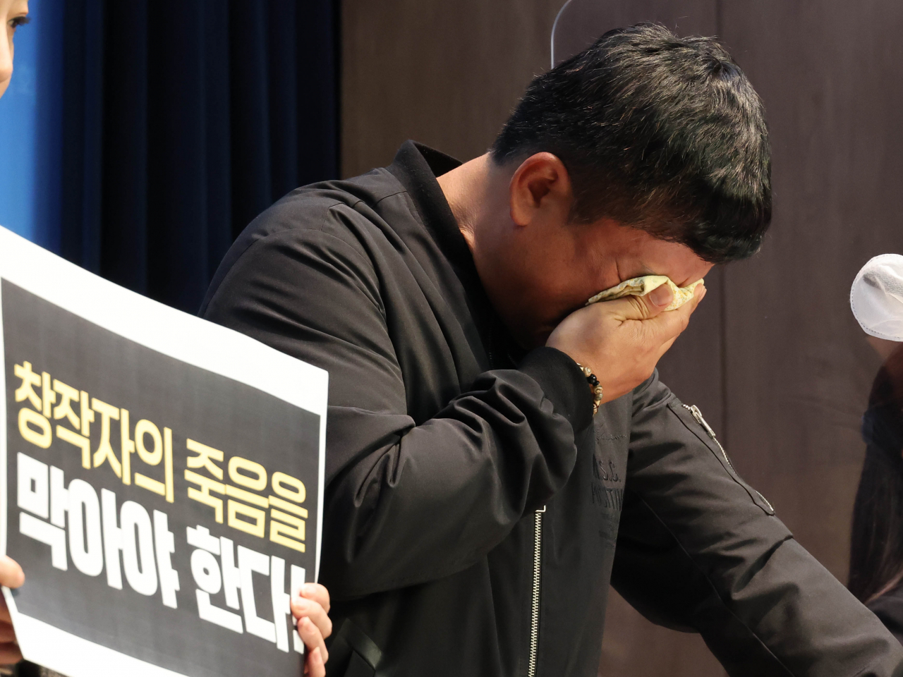 Lee Woo-jin, the co-creator of “Black Rubber Shoes” and the deceased cartoonist Lee Yoo-young's younger brother, gets emotional during a press conference at the National Assembly in Seoul on Monday. (Yonhap)