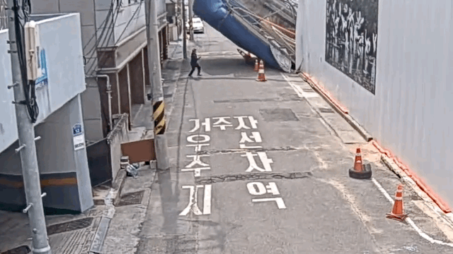 A man escapes a falling pile driver at an alley next to the construction site in Ulsan on Wednesday. (Ulsan Namgu Office)