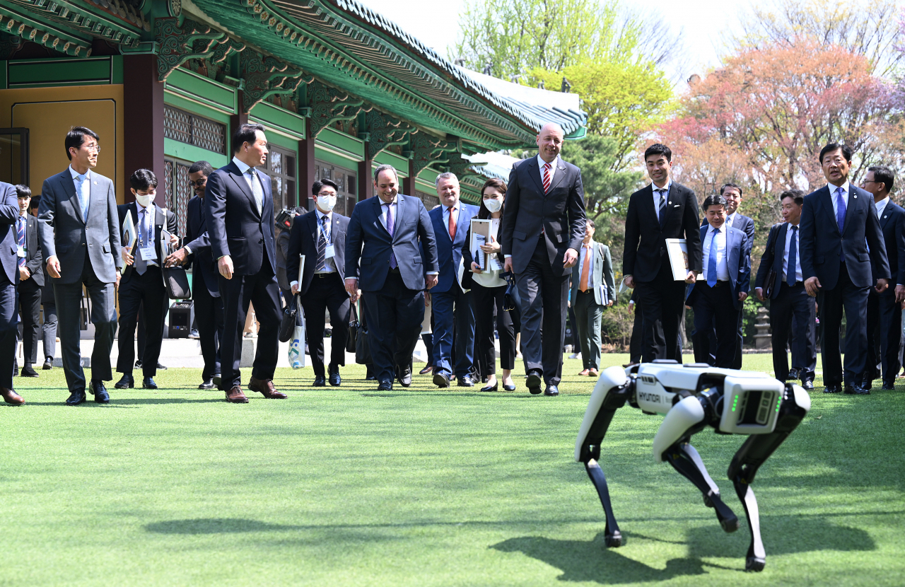 ROBOT GUIDE TO BUSAN EXPO – Delegates from the International Bureau of Expositions (BIE), led by Patrick Specht, president of the BIE Administration and Budget Committee, and Korean business leaders, including SK Group Chairman Chey Tae-won, are guided by the four-legged walking robot Spot to the venue of a luncheon hosted by the Busan Expo Bidding Committee at the Shilla Seoul on Monday. The robot, developed by Hyundai Motor Group-owned Boston Dynamics, was deployed to the site in line with Korea’s theme for the World Expo in 2030: “Transforming Our World, Navigating Toward a Better Future.” (Yonhap)