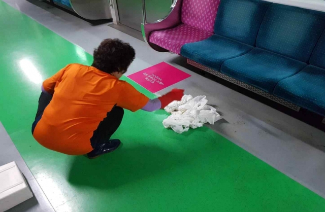 A Seoul Metro staff member cleans up throw-up on the floor of a subway car. (Seoul Metro)