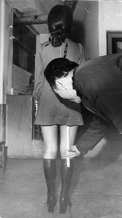 This undated photo depicts an individual inspecting the length of a woman's skirt. (News Photography Yearbook)
