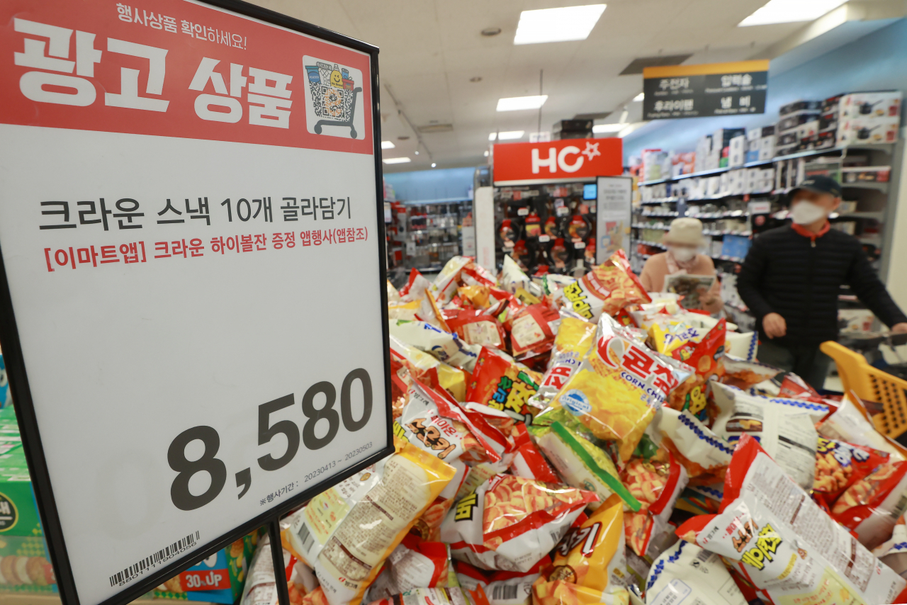 SNACK BINGE – Snacks are piled up for a “bulk purchase” event at Emart in Yongsan, Seoul, Thursday. Retailers are going for bargain events to lure customers with a tight budget amid prolonged inflation woes. The sign reads 