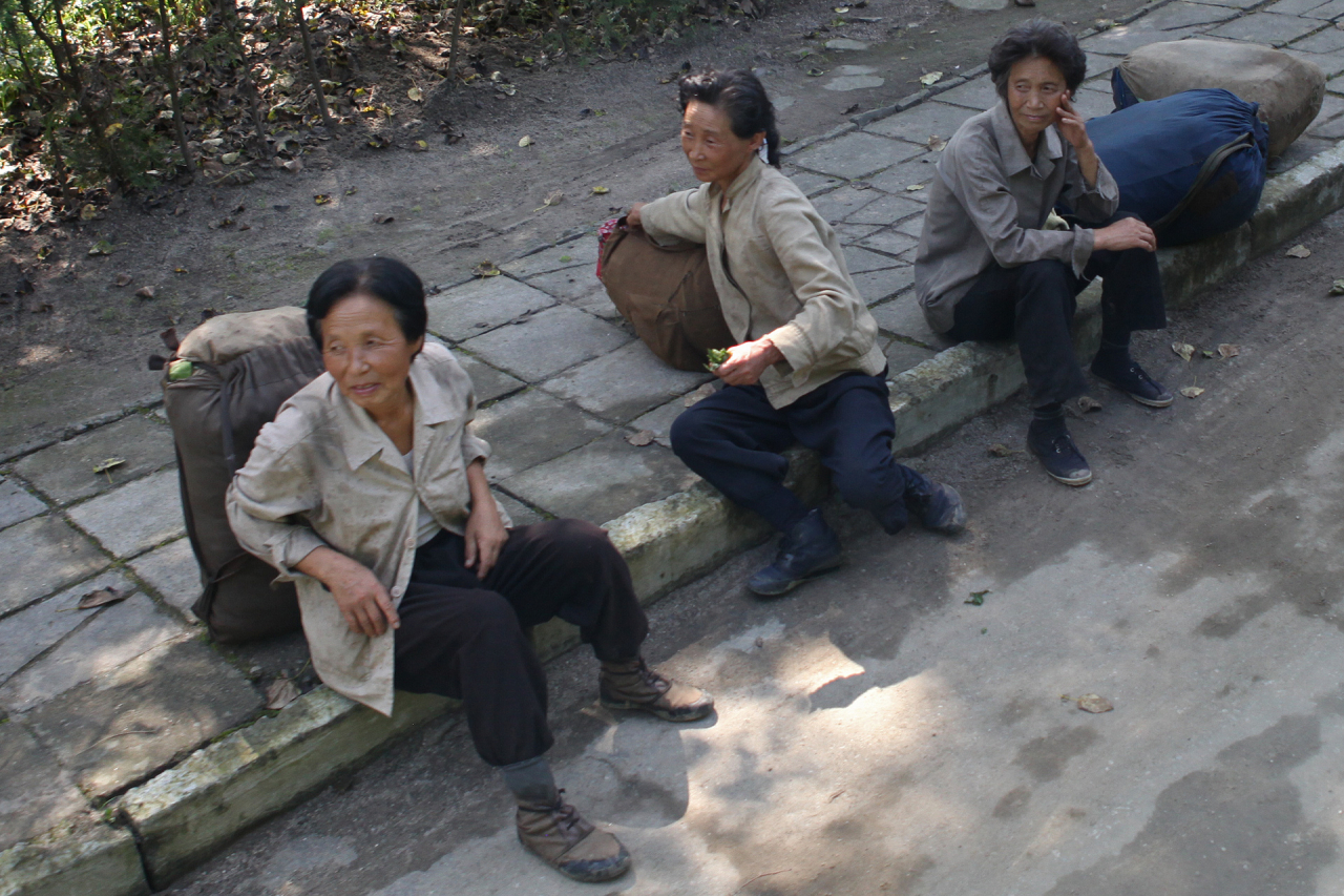 Street vendors sit on a sidewalk in Samjiyon County, Ryanggang province, North Korea, in September 2010. (Photo Courtesy of Roman Harak)