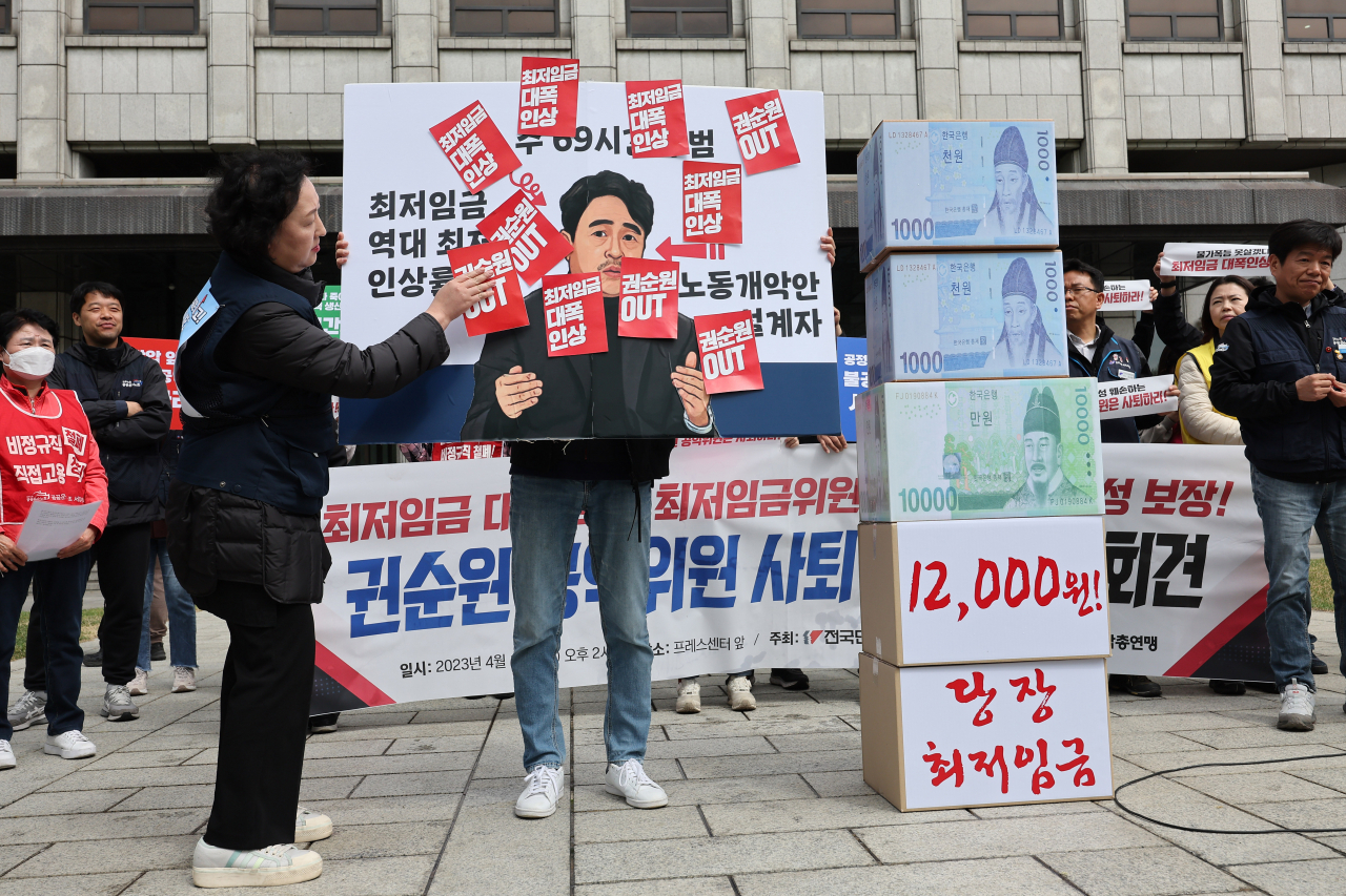 Labor activists hold a demonstration to demand next year's minimum hourly wage be set at 12,000 won ($9.10) in front of the Press Center in Seoul on April 18, 2023, where the Minimum Wage Commission is set to hold the commission's first plenary session. The commission failed to hold the meeting as the commission's head and other members representing public interests failed to attend it in protest of a labor activists' rally at the meeting. The 27-member commission, comprising nine each from three sides -- employers, employees and those representing social interests -- holds plenary meetings around this time every year to decide the following year's minimum wage. (Yonhap)