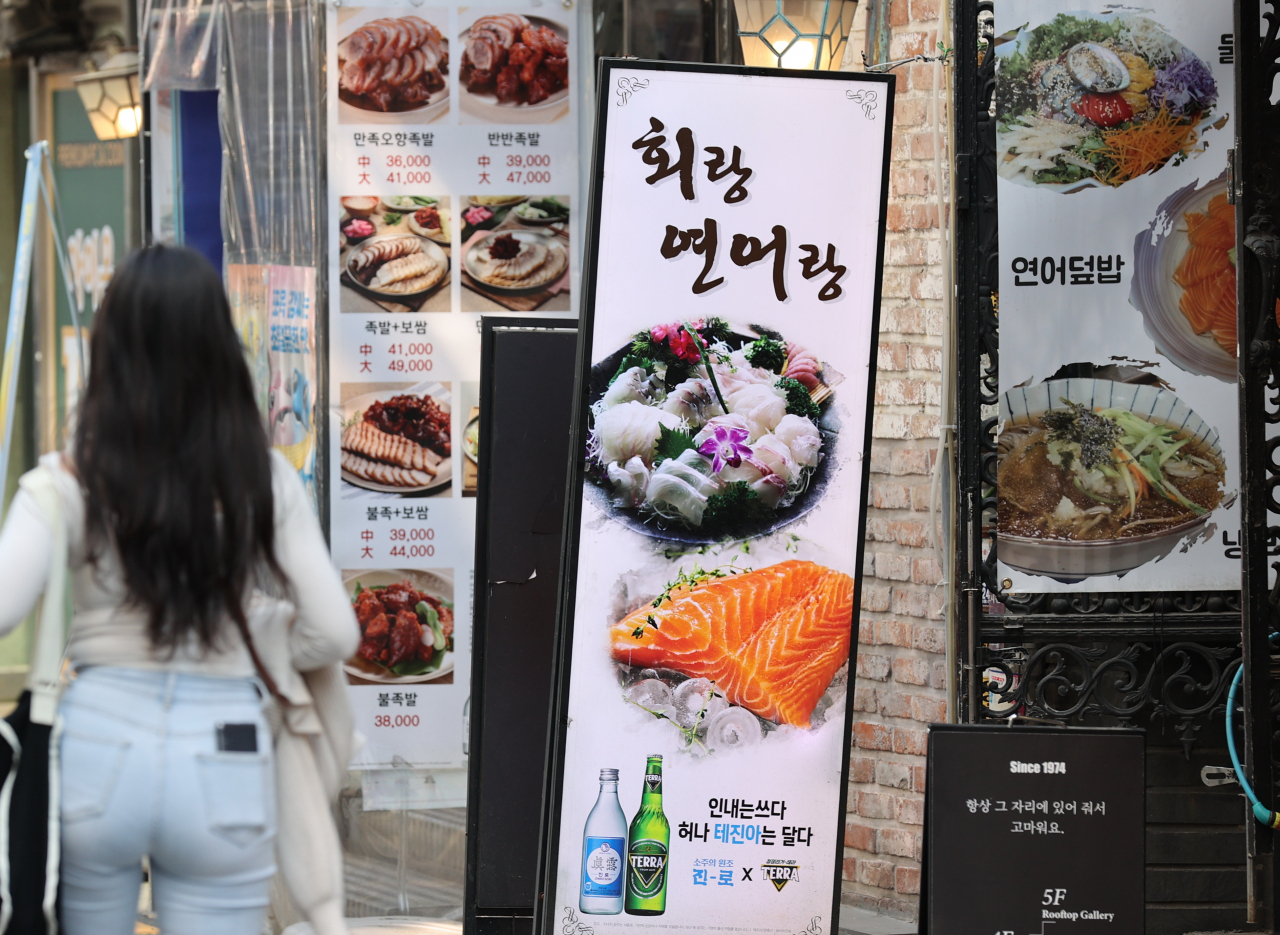 A woman looks at the menus of restaurants in Seoul in this April 2 file photo. (Yonhap)
