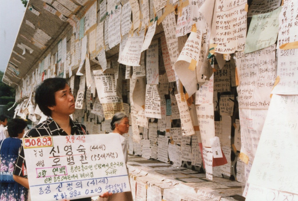 A man holds a signboard that shows the names and other information of his family members lost during the Korean War. (KBS)