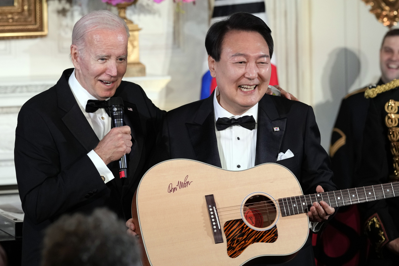 US President Joe Biden surprises South Korean President Yoon Suk Yeol with a guitar signed by Don McLean in the State Dining Room of the White House in Washington, Wednesday, following the State Dinner. 