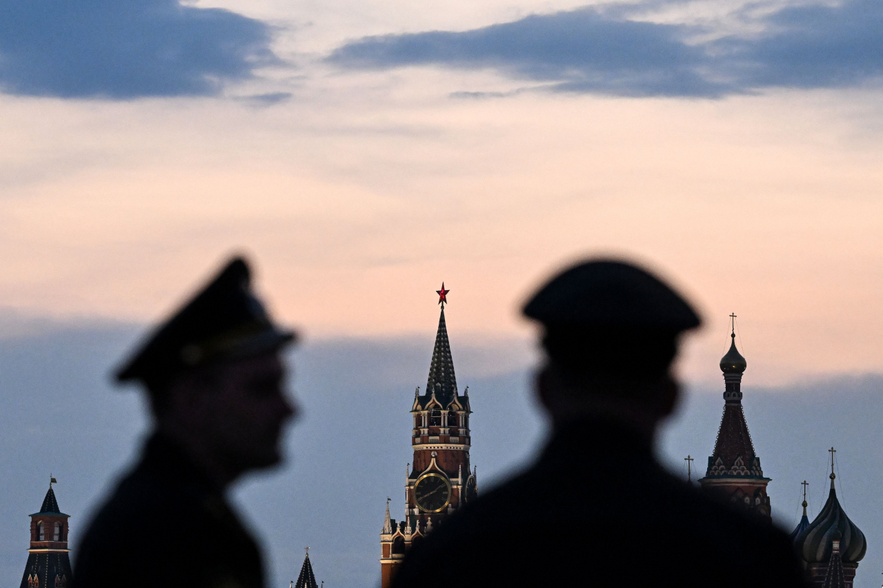 Russian servicemen stand with the Kremlin's Spasskaya tower and Saint Basil's cathedral before the Victory Day military parade rehearsal in central Moscow, on Thursday. (AFP-Yonhap)