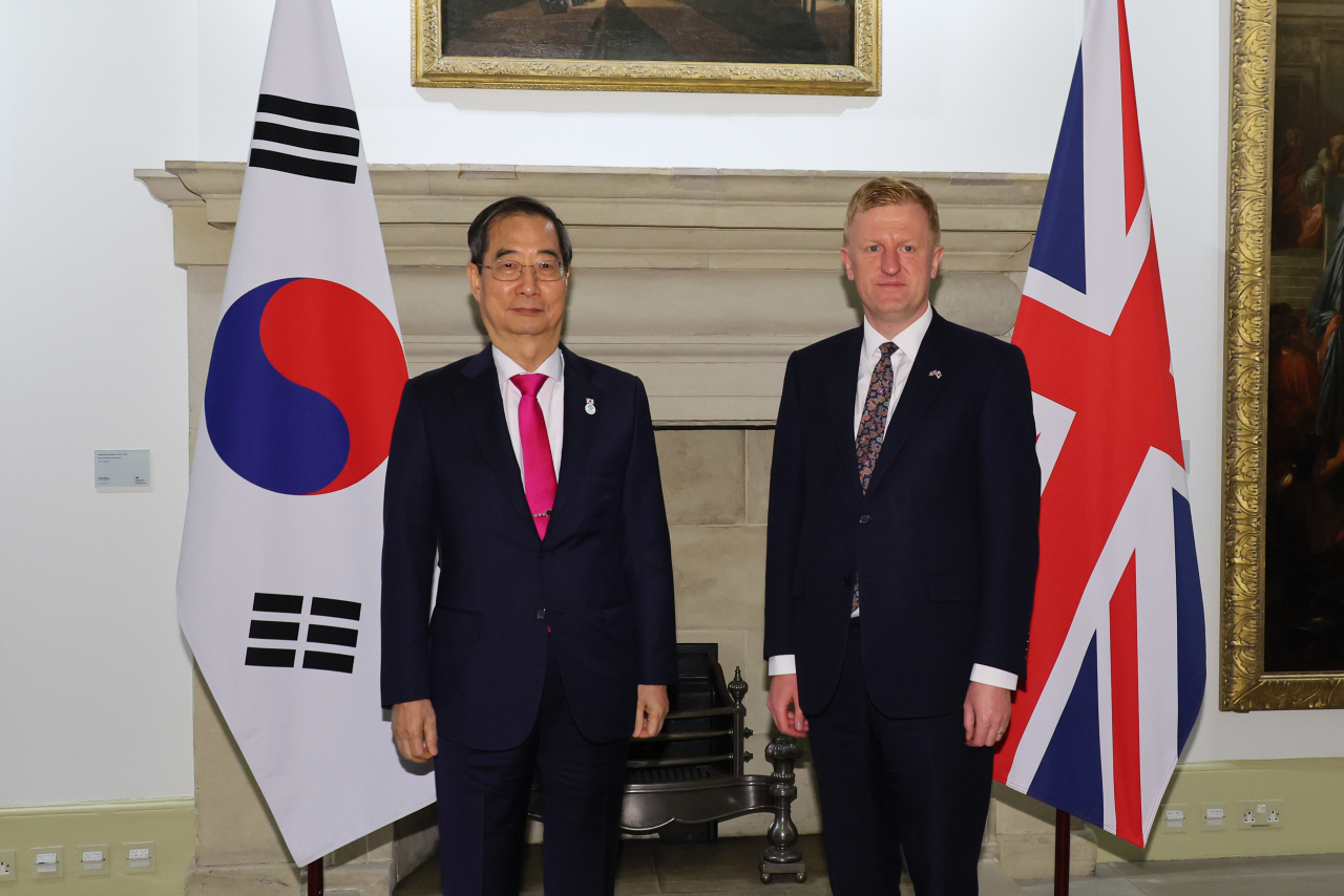 South Korean Prime Minister Han Duck-soo poses for photos with Britain's Deputy Prime Minister Oliver Dowden before their meeting at Dowden's office in London on Friday. (Pool Photo) (Yonhap)