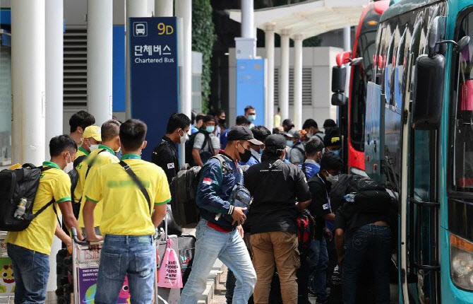 Foreign workers board a chartered bus at Incheon Airport (Yonhap)