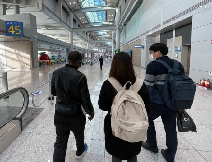 This photo shows an African asylum seeker who lived inside Incheon Airport for more than a year 2020-2021 walking in the transit zone with officials from Duroo, a group of public interest lawyers in South Korea. (Duroo)