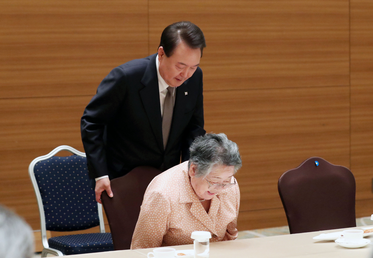 South Korean President Yoon Suk Yeol (left) helps a Korean victim of the 1945 Hiroshima atomic bombing take a seat during a meeting with a group of Korean victims at a hotel in Hiroshima, Japan, on May 19, 2023. (Yonhap)