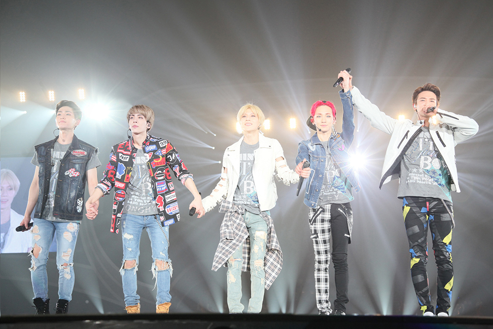 SHINee members, (from left) Onew, Jonghyun, Taemin, Key and Minho, hold hands on stage during the band's 2015 Tokyo Dome debut concert. (SM Entertainment)