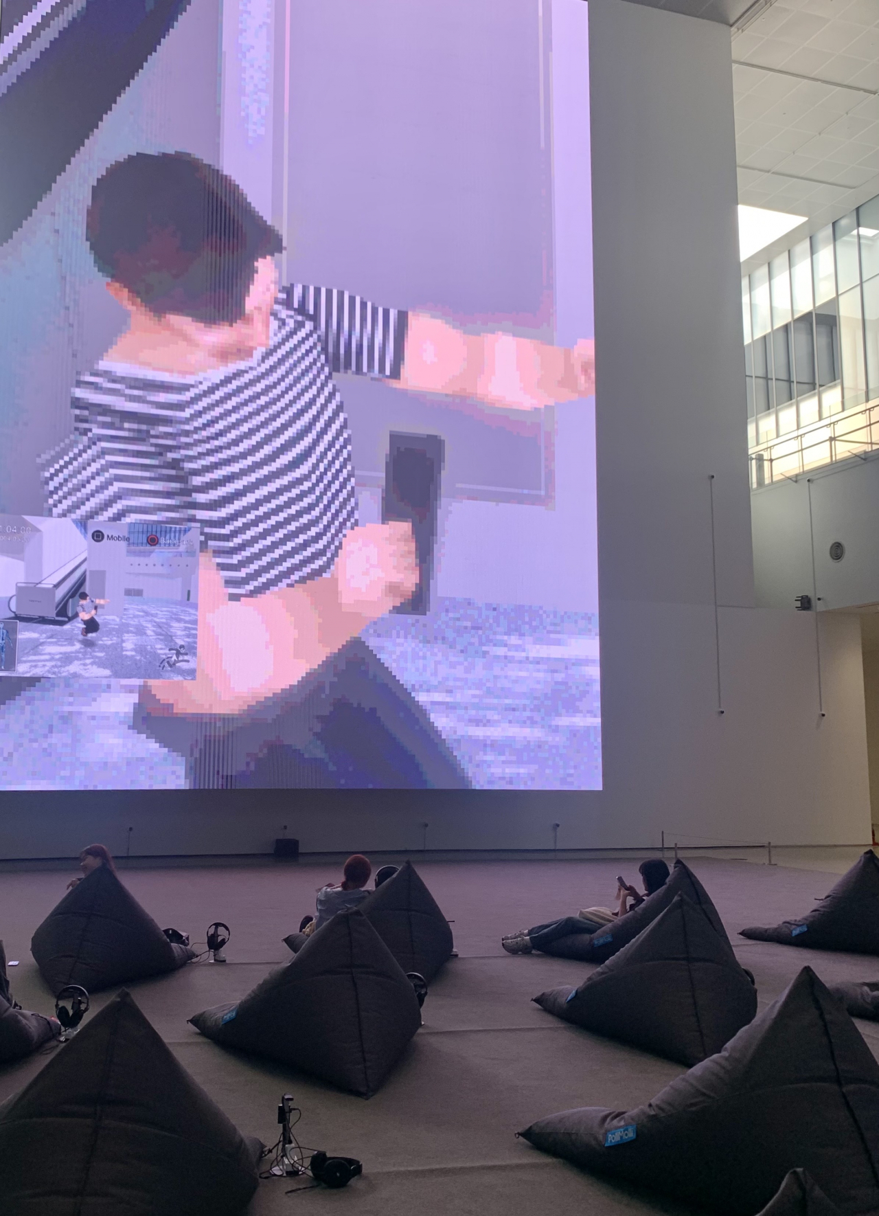 Visitors sit on bean bag chairs and watch Kim Heecheon's 