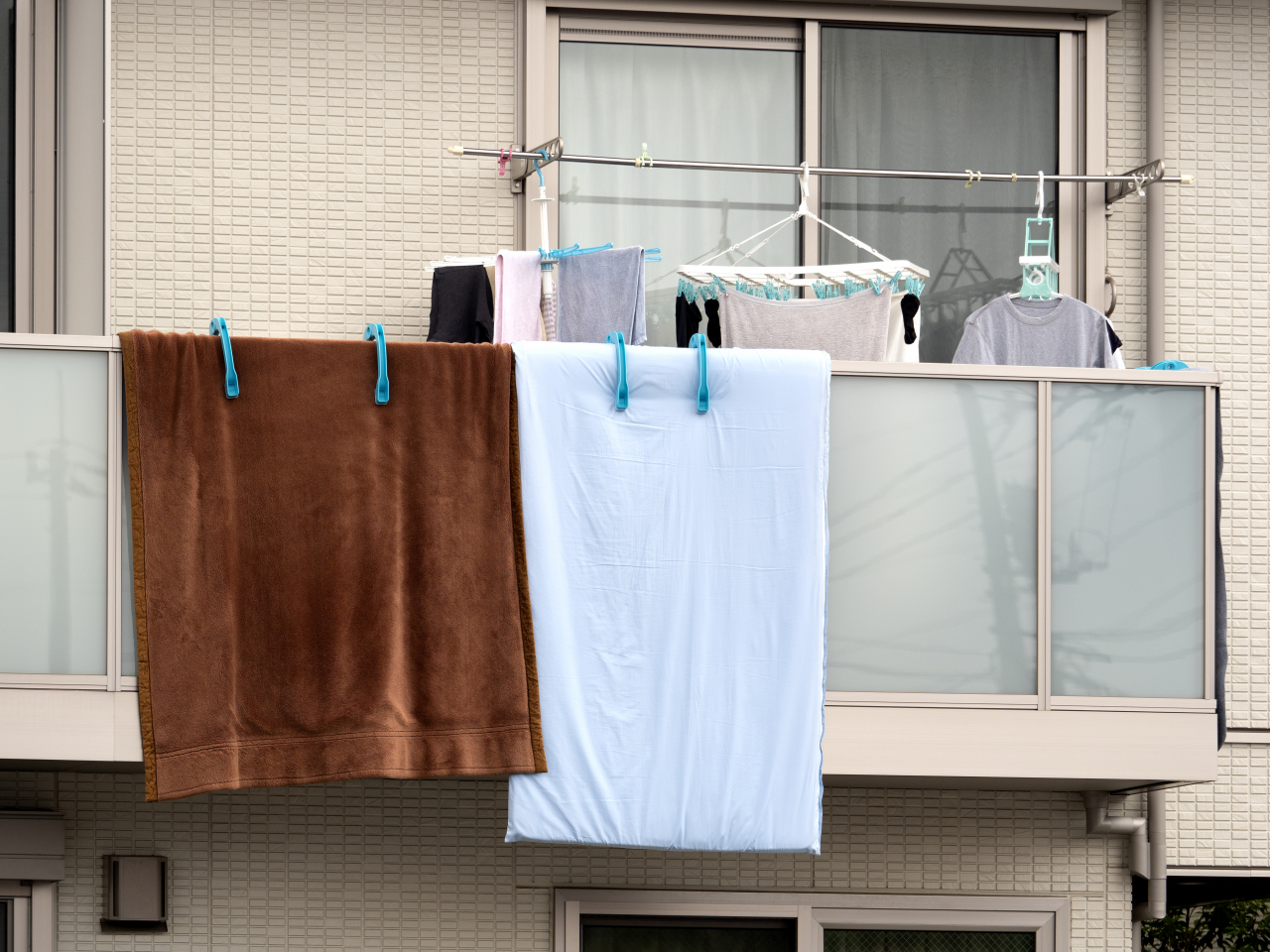 A blanket and comforter hang over the balcony of an apartment unit. (Getty Images)