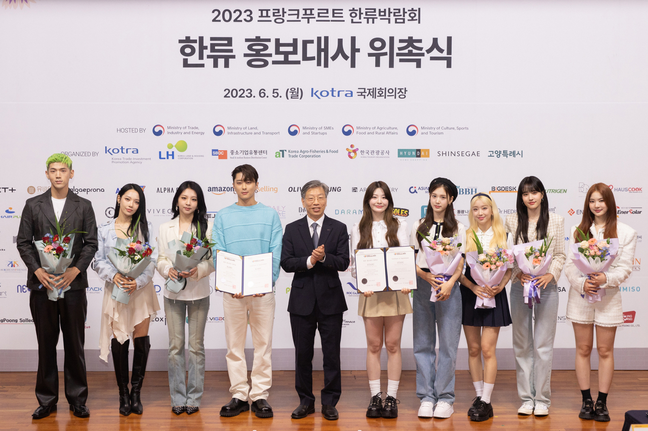 KOTRA CEO Yu Jeoung-yeol (fifth from left) poses for a picture with K-pop groups Kard (on Yu's left) and StayC, the ambassadors for the Korea Brand and Entertainment Expo 2023, Frankfurt, at the appointment ceremony held at KOTRA headquarters in Seoul on Monday. (KOTRA)