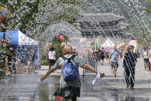 People pass through the water fountain at Gwanghwamun Plaza in central Seoul on May 17. (Yonhap)