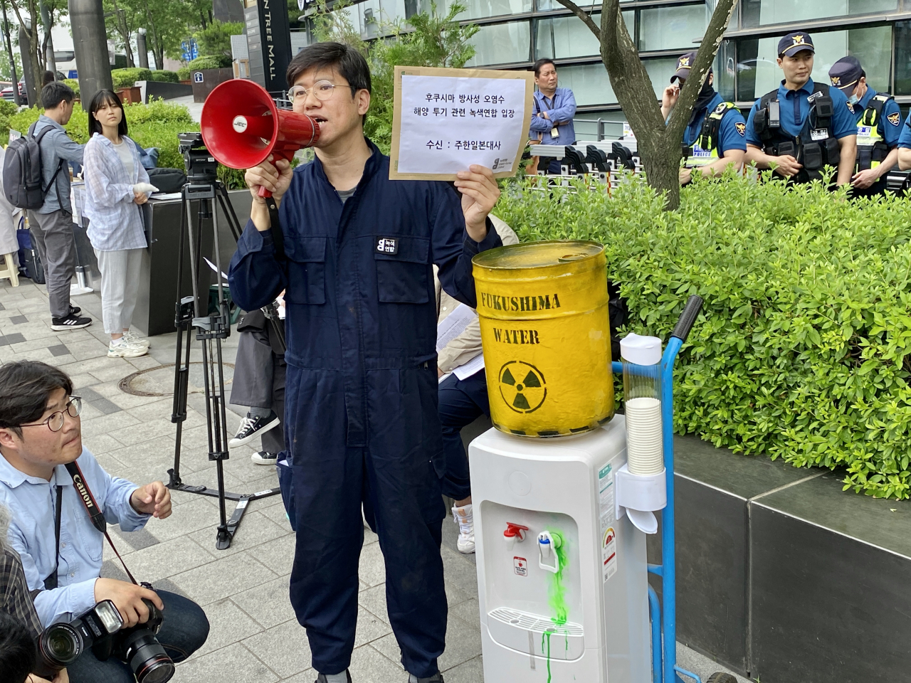 An activist from the environmental group Green Korea United staged a protest in front of the Embassy of Japan in Seoul, standing next to a water purifier attached to a mock barrel of contaminated Fukushima wastewater on June 7, 2023. (Herald DB)