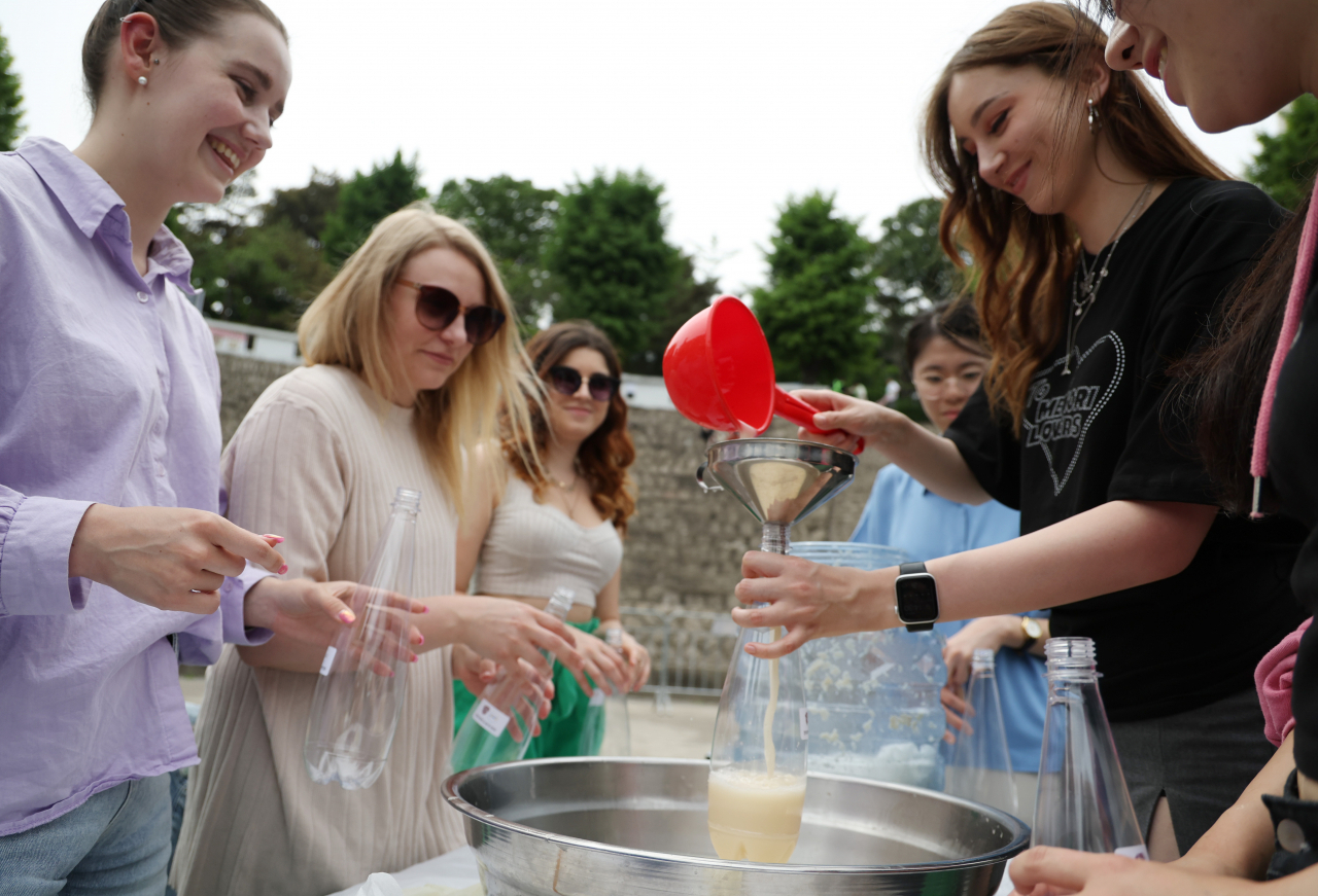 Exchange students at Kyung Hee University take part in a makgeolli-making experience inside the campus during the university festival in May. (Yonhap)