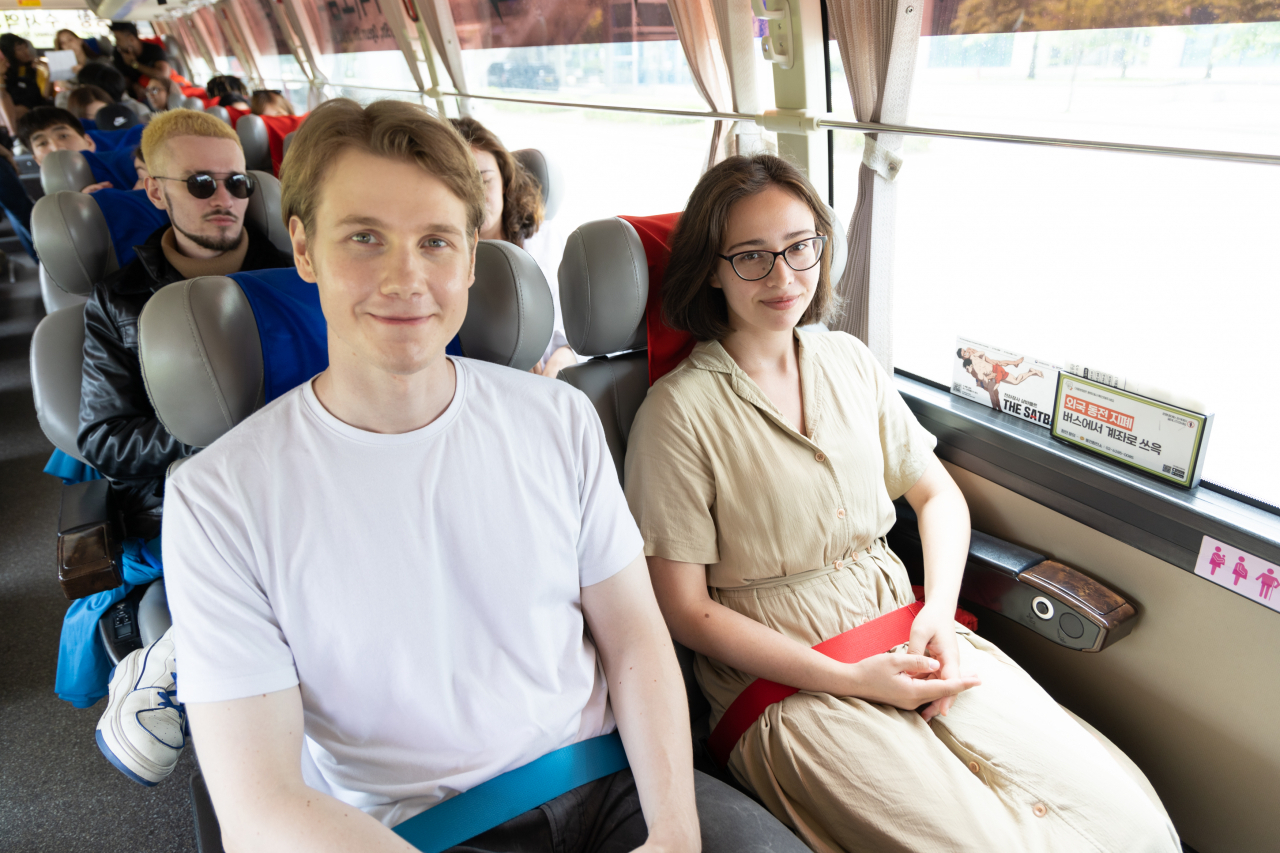 People sit on a bus with safety belts inspired by traditional Korean wrestling bands during a bus ride from Incheon Airport to central Seoul on June 20. The Ministry of Culture, Sports and Tourism announced that the 