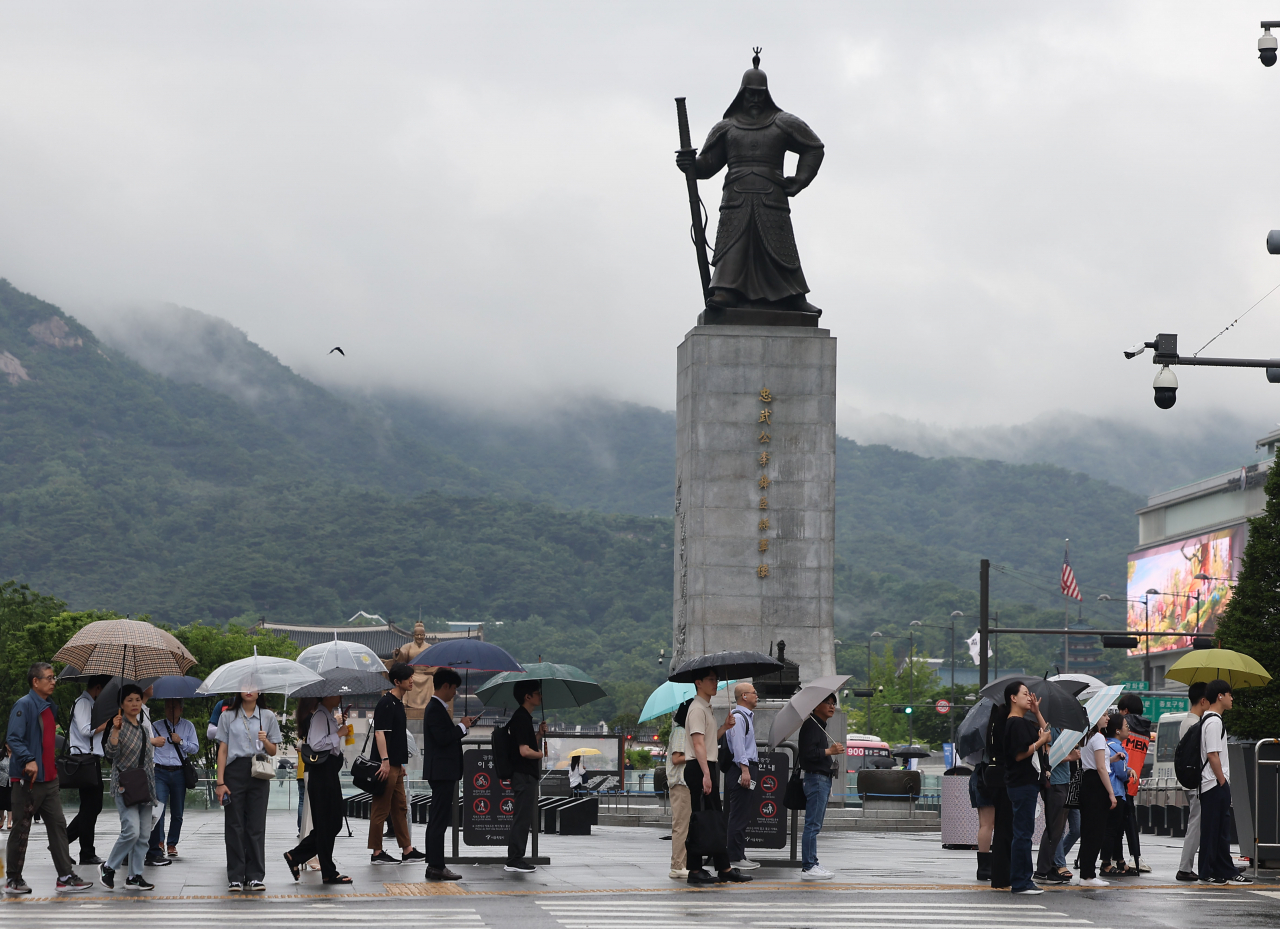 People walk with umbrellas on Gwanghwamun Square in central Seoul on Monday, as the annual monsoon season kicked off nationwide. (Yonhap)