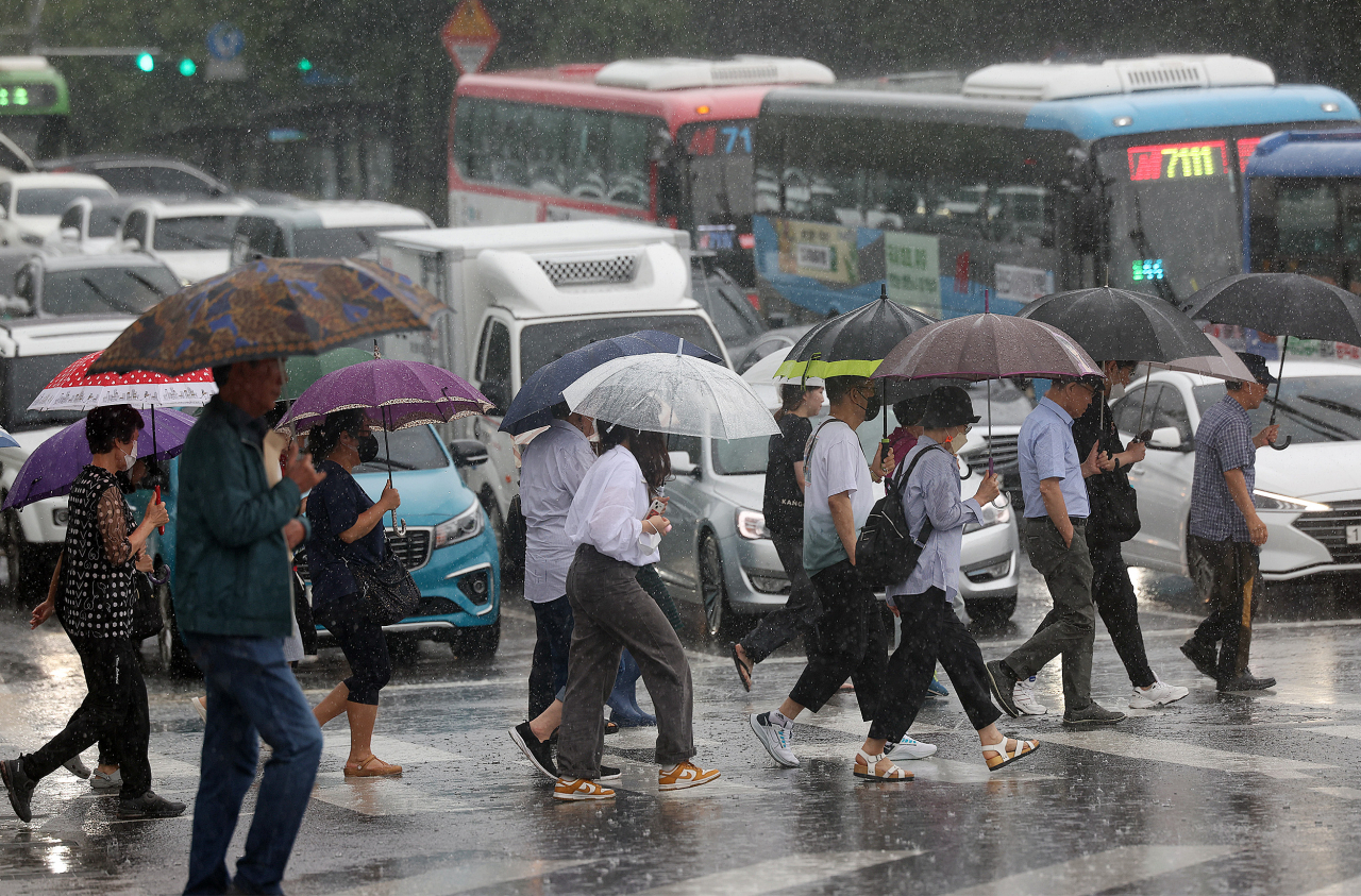 People walk at a crosswalk with umbrellas in front of Yonsei University in Seodaemun-gu, Seoul, Thursday, when heavy rain warnings were issued throughout Seoul and the metropolitan area. (Yonhap)
