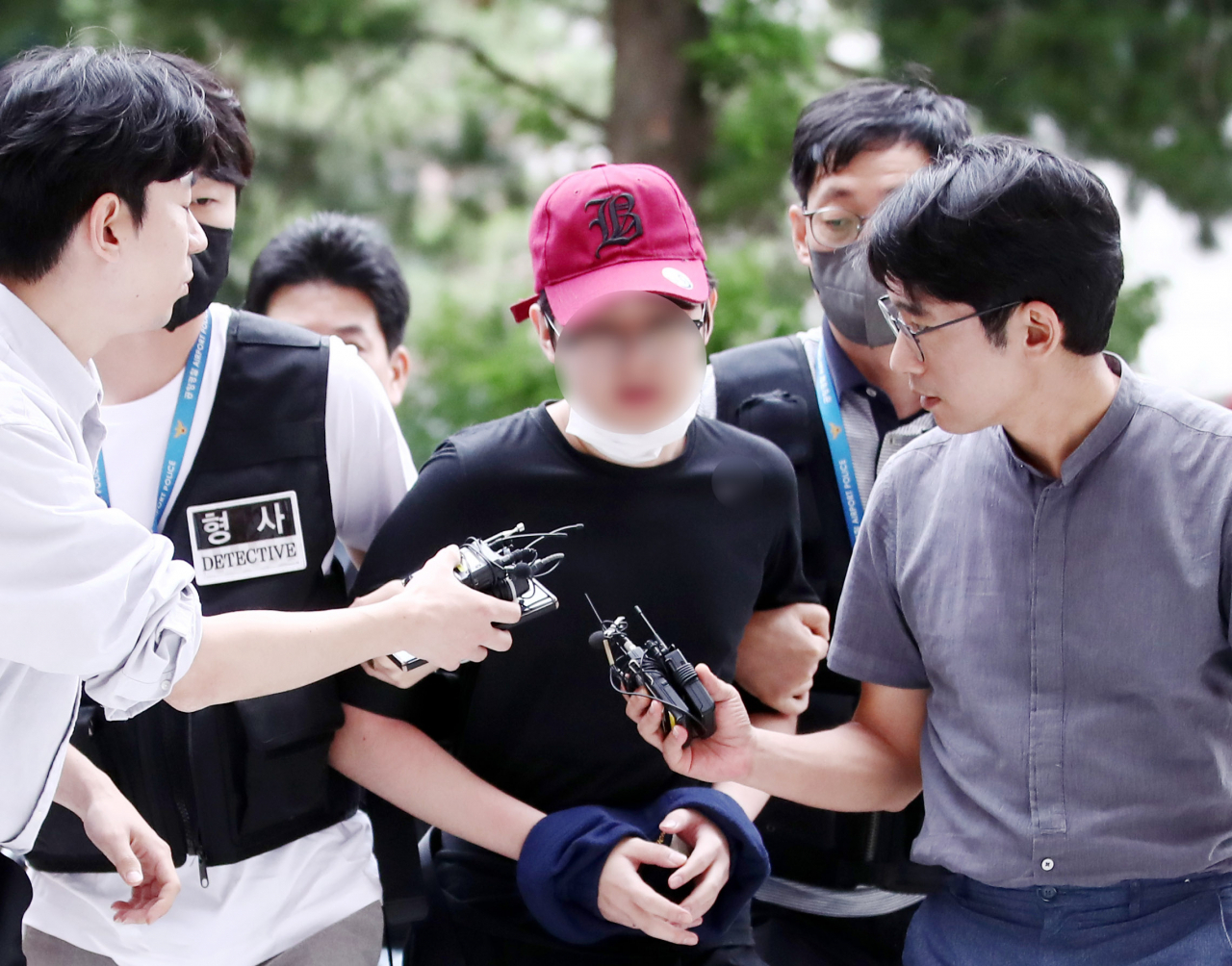 Reporters question a 19-year-old accused of attempting to open an emergency door of a plane during flight at the Incheon District Court in Incheon on June 20, before attending his arrest warrant hearing. (Yonhap)