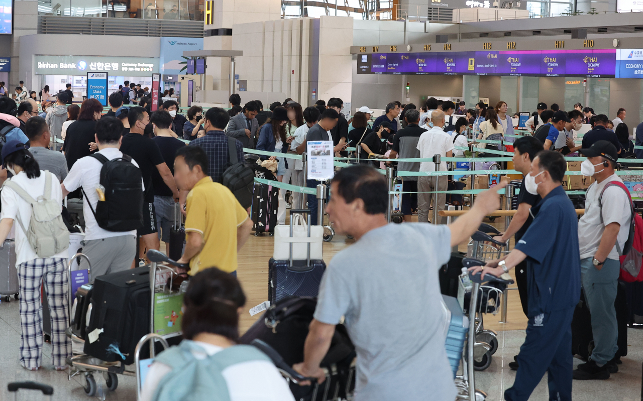 People wait in line in front of check-in counter at Incheon International Airport, Incheon, Sunday. (Yonhap)