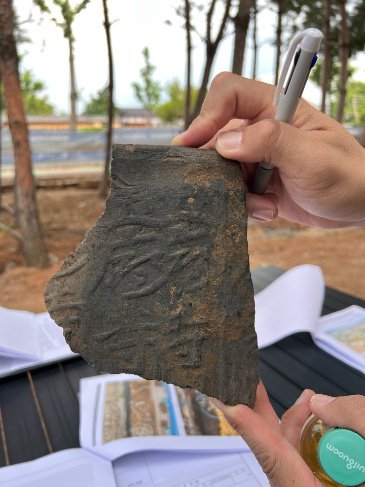 A researcher holds a roof tile fragment with 