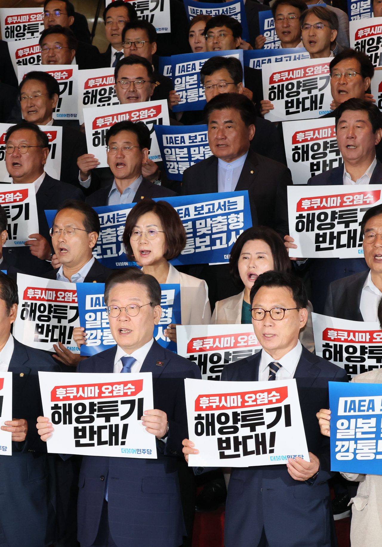 Lee Jae-myung (2nd from left, 1st row), leader of the main opposition Democratic Party, and other party lawmakers chant slogans during a rally at the National Assembly in Seoul on Wednesday, to voice their objection to Japan's planned discharge of treated radioactive water from the crippled nuclear reactors in Fukushima into the ocean. The rally came one day after the International Atomic Energy Agency presented its conclusion that the Japanese plan is consistent with its safety standards. (Yonhap)