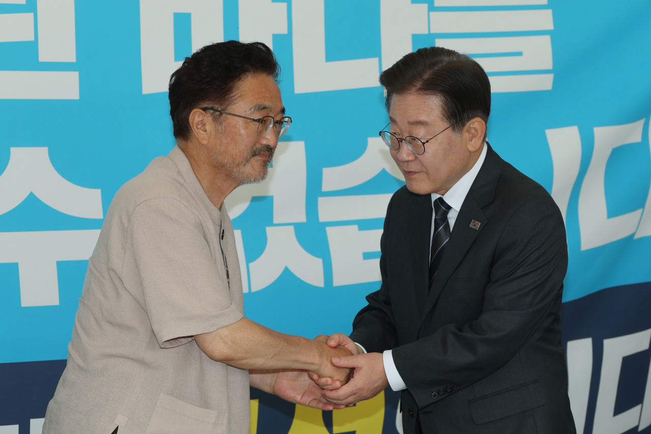 Democratic Party of Korea Rep. Woo Won-shik (left) shakes hand with party leader Rep. Lee Jae-myung as he was on a hunger strike near the National Assembly on Monday. (Yonhap)