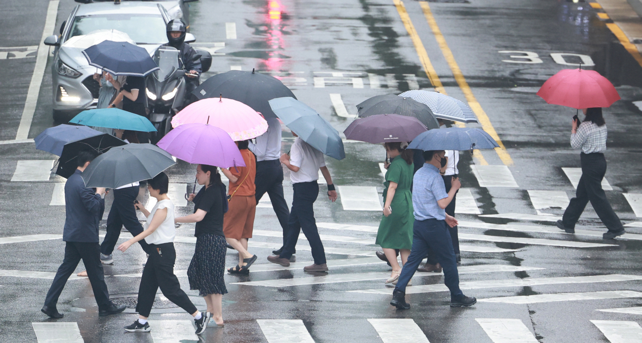 People walk at a crosswalk with umbrellas, Jongno-gu, Seoul, Tuesday. (Yonhap)
