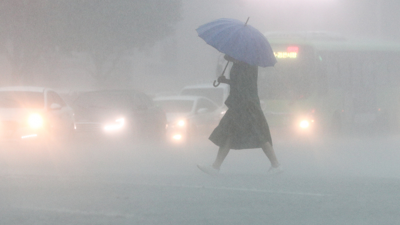 A person puts up an umbrella while crossing a street in Daegu, about 240 kilometers southeast of Seoul, on Tuesday due to heavy rain. (Yonhap)