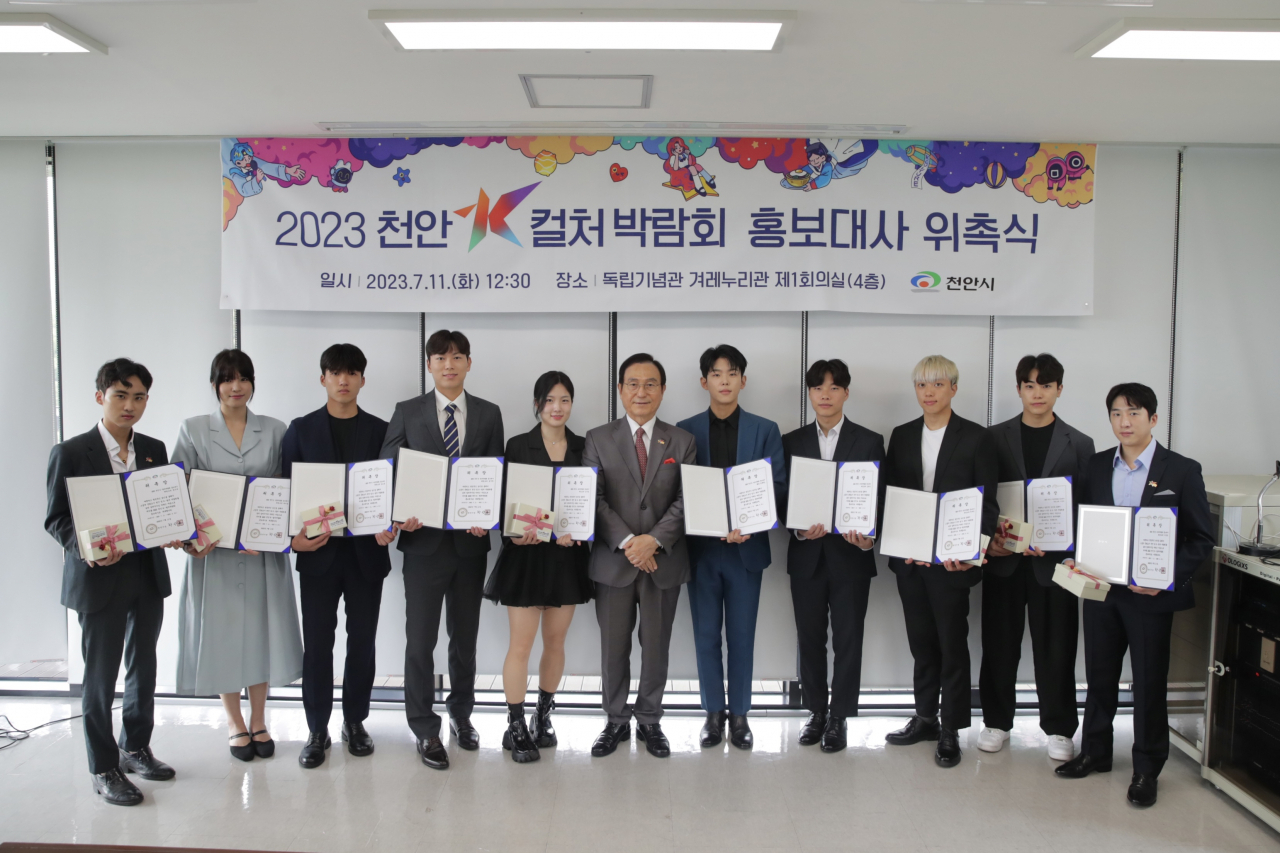 Members of Taekwoncre, Cheonan Mayor Park Sang-don (center) and Paul Kim (seventh from left) pose for photos at the Independence Hall of Korea in Cheonan, South Chungcheong Province on Tuesady. (Cheonan City)
