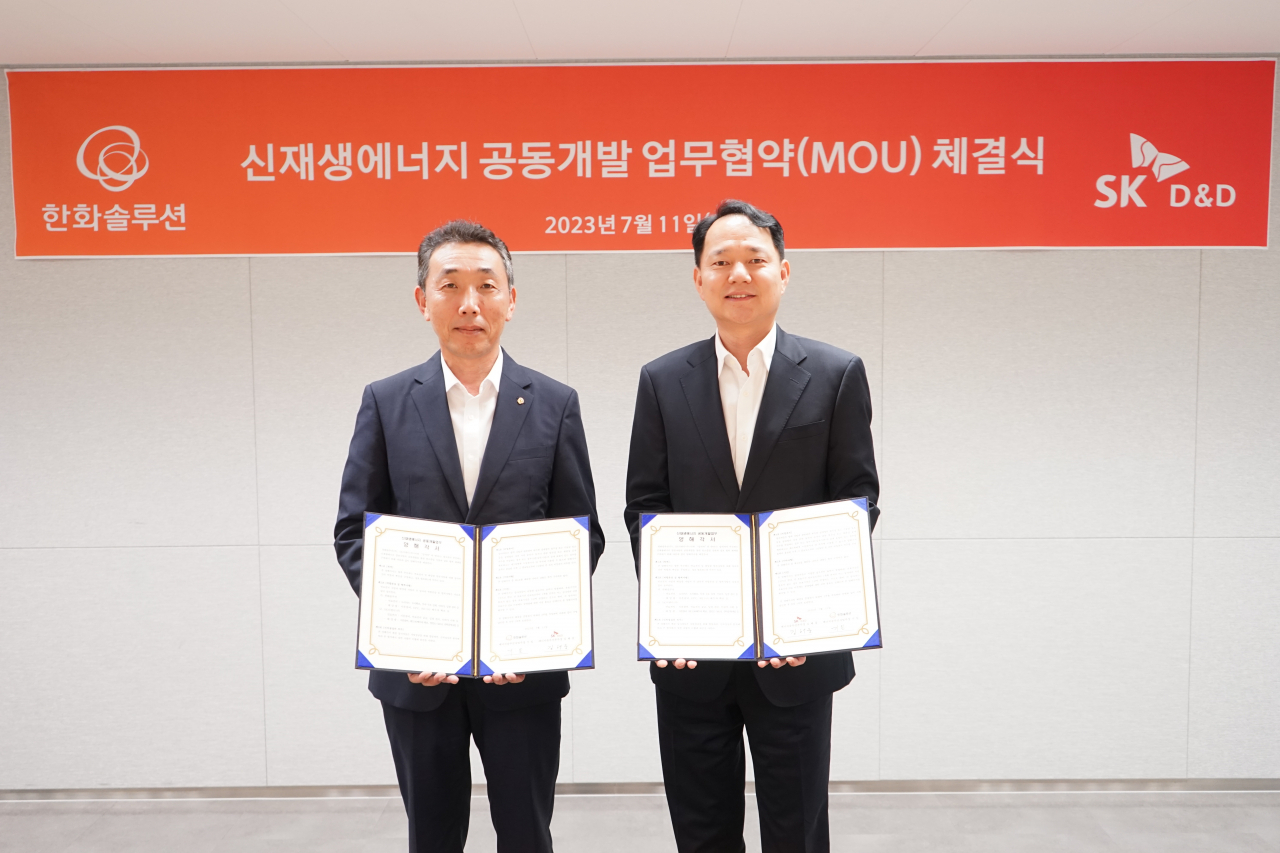 Gi Il(left), head of the energy solution business unit at Hanwha Solutions, and Kim Han-zoong, head of the energy solution division at SK D&D, pose for a photograph during the partnership signing ceremony held at Hanwha's headquarters in Seoul on Tuesday. (Hanwha Solutions)