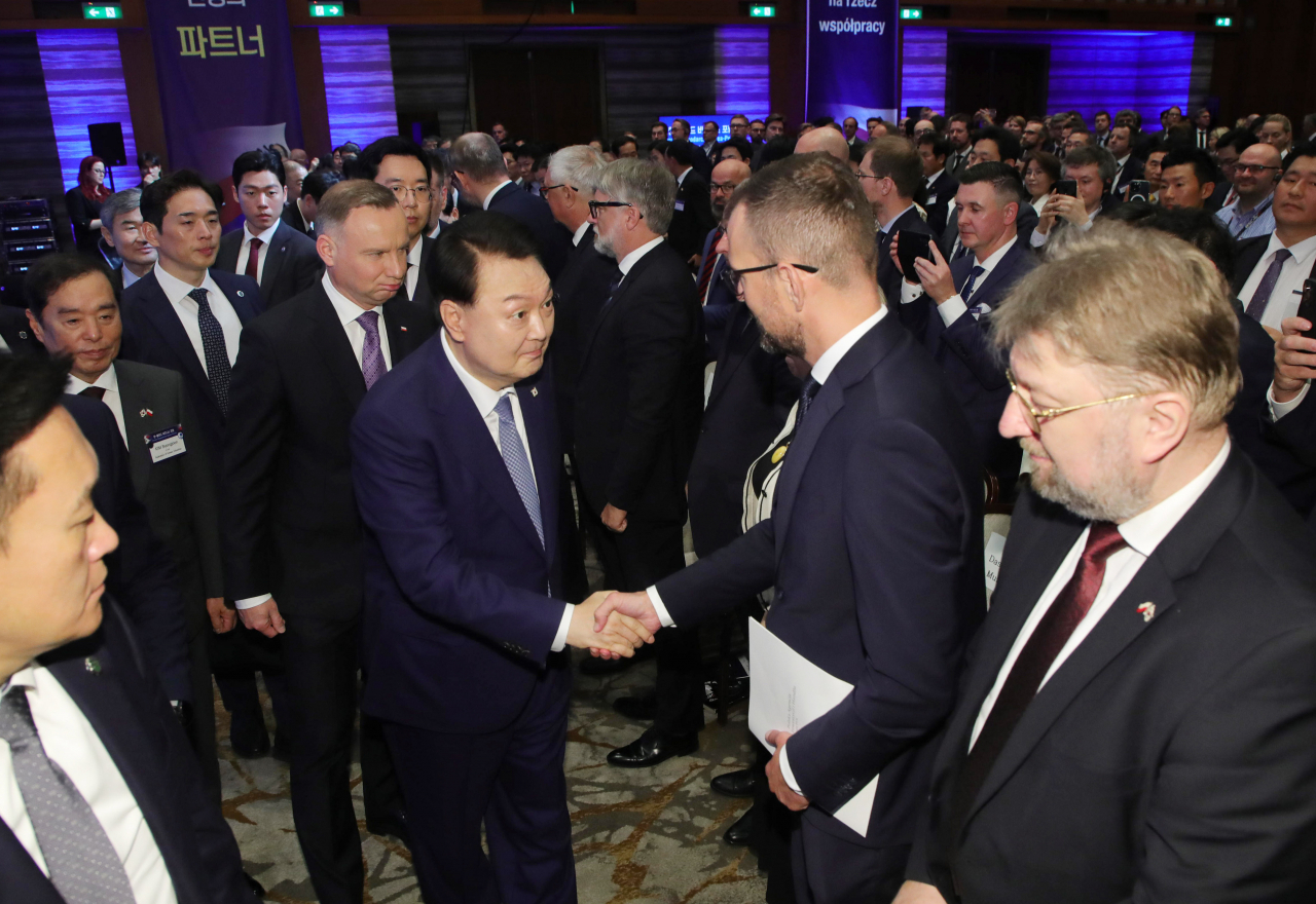 President Yoon Suk Yeol, currently on an official visit to Poland, and Polish President Andrzej Duda greet attendees on Friday after delivering speeches at the Korea-Poland Business Forum held at a hotel in Warsaw. (Yonhap)