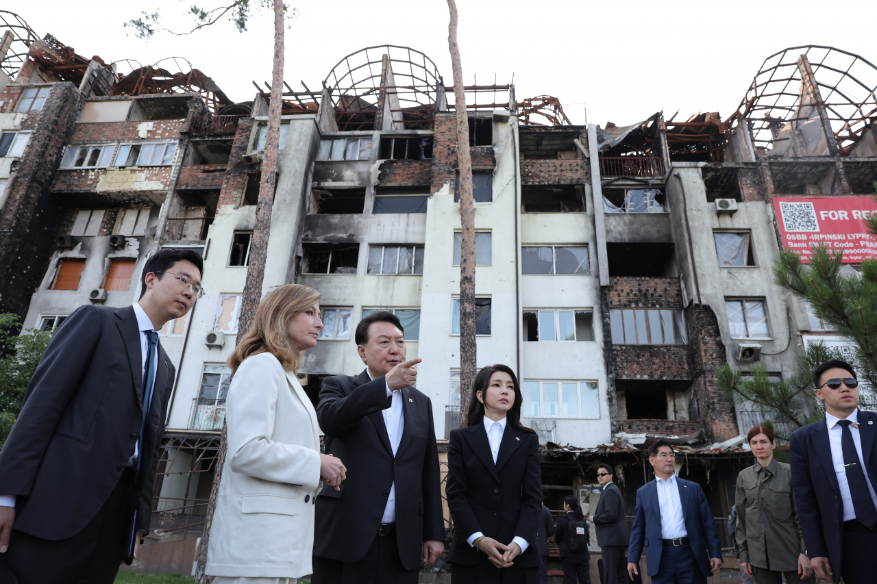 President Yoon Suk Yeol and first lady Kim Keon Hee, who made a surprise visit to Ukraine after an official state visit in Warsaw, the capital of Poland, visit the site of the bombing of a private house in Irpin near Kyiv on Saturday. (Yonhap)